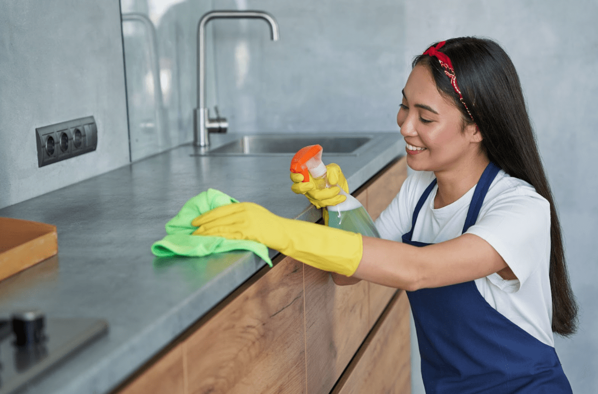 professional maid cleaning kitchen countertop to maintain stone surface